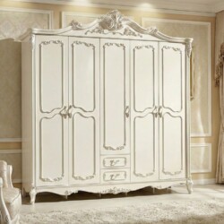 Tủ quần áo 5 cánh tân cổ điển màu trắng ngọc trai, chụp chính diện trong phòng ngủ sáng sủa. Tủ có các đường phào chỉ và h…