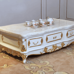 Bàn trà tân cổ điển BTA98-16 chụp từ góc thấp, hơi chếch bên phải, đặt trên thảm họa tiết vàng. Bàn có mặt đá tự nhiên vân…