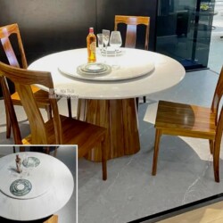 Ảnh chụp tổng thể bộ bàn ăn tròn gỗ Mun hiện đại BAT106-130 từ góc hơi chếch, đặt trong không gian showroom. Bàn có mặt đá…