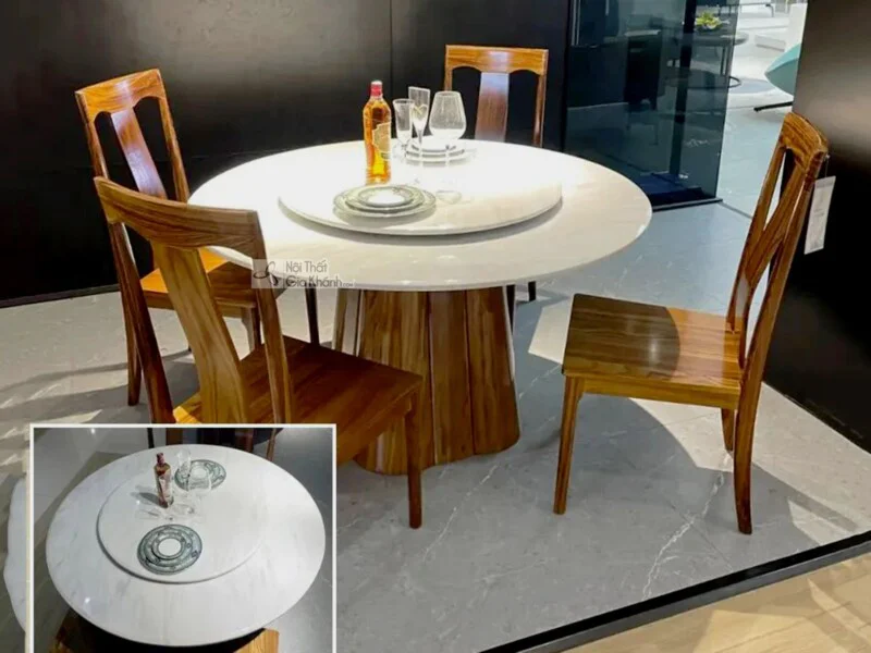 Ảnh chụp tổng thể bộ bàn ăn tròn gỗ Mun hiện đại BAT106-130 từ góc hơi chếch, đặt trong không gian showroom. Bàn có mặt đá…
