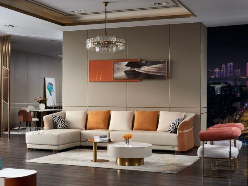 Bộ sofa góc chữ L màu kem nhạt, bọc da Nappa cao cấp, đặt trong phòng khách phong cách hiện đại luxury. Sofa có tựa lưng t…