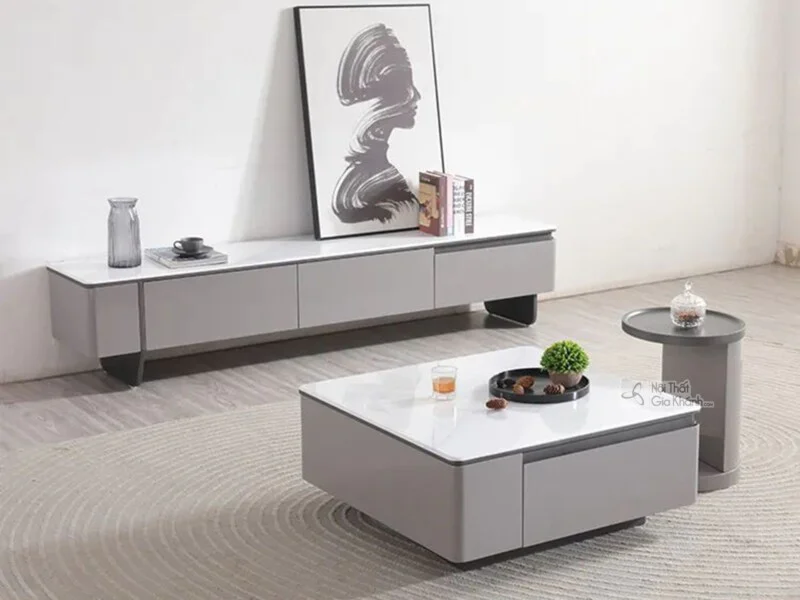 Bộ bàn trà và kệ tivi hiện đại BTK9870-1 được chụp từ góc chính diện, hơi chếch cao, đặt trong không gian phòng khách tối…