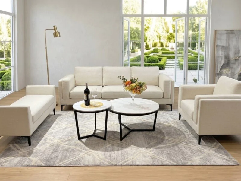 Tổng thể không gian phòng khách hiện đại với bộ bàn trà đôi chân Y cao đặt giữa bộ sofa màu kem. Hai bàn tròn mặt đá trắng…