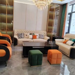 Toàn cảnh bộ sofa luxury SFQ626-1123 được sắp đặt trong phòng khách hiện đại, chụp từ góc chính diện. Hai ghế đơn màu cam…