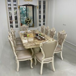 Bộ bàn ăn BAT-29H với 8 ghế, chụp cận cảnh từ góc chéo, làm nổi bật mặt bàn đá vân vàng nâu sang trọng. Chân bàn và khung…