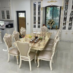 Toàn cảnh bộ bàn ăn BAT-29H với 8 ghế, chụp từ góc rộng hơn, cho thấy không gian phòng ăn liền kề khu vực bếp. Bàn ăn mặt…