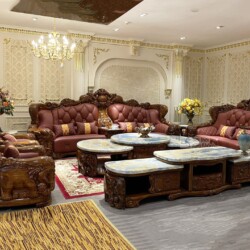 Toàn bộ không gian phòng khách với bộ sofa gỗ mun lớn, góc chụp từ phía sau bên trái. Các băng ghế dài, ghế đơn, bàn trà v…