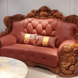 Cận cảnh băng sofa hai chỗ ngồi màu nâu đỏ, bọc da bò tót cao cấp, với khung gỗ mun Nam Phi được chạm khắc hoa văn cầu kỳ…