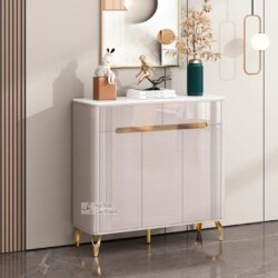 Tủ giày hiện đại TDEH165 màu kem bóng, đặt ở góc tiền sảnh. Tủ có mặt trên bằng đá màu trắng, ba cánh cửa tủ với các đường…