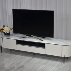 Kệ tivi Verona KTKD9863-20 đặt trong không gian phòng khách đơn giản với rèm trắng. Kệ có mặt đá vân trắng, thân màu kem b…
