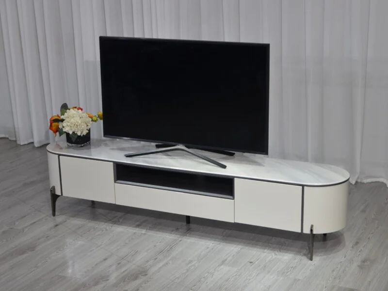Kệ tivi Verona KTKD9863-20 đặt trong không gian phòng khách đơn giản với rèm trắng. Kệ có mặt đá vân trắng, thân màu kem b…