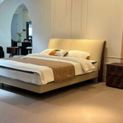 Giường ngủ bọc da nhập khẩu GIC191-18 được chụp từ góc chếch, nổi bật với đầu giường cao bọc da màu kem nhạt, có các đường…