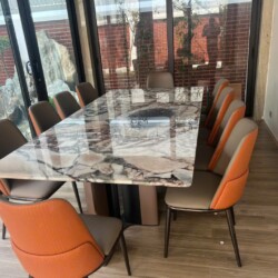 Bàn ăn mặt đá tự nhiên BAQ55-24 được đặt trong không gian phòng ăn hiện đại, cạnh cửa kính lớn nhìn ra sân vườn. Mặt bàn h…