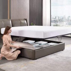 Giường ngủ thông minh GI02GK-18 màu nâu xám, chụp cận cảnh tính năng hộc đựng đồ dưới đệm. Một phụ nữ đang sắp xếp chăn ga…