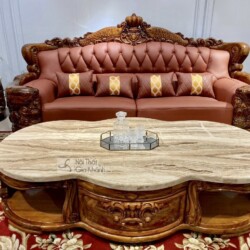 Cận cảnh bàn trà chính hình bầu dục với mặt đá cẩm thạch vân mây tự nhiên, đặt trước ghế sofa băng dài. Khung bàn làm từ g…