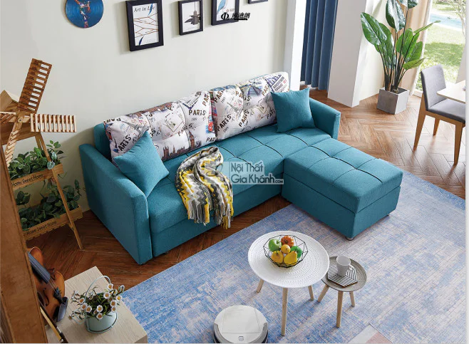 Ghế sofa giường lệch góc đa năng SF119B-31 màu xanh ngọc bọc vải, được chụp từ trên cao trong một phòng khách hiện đại. So…