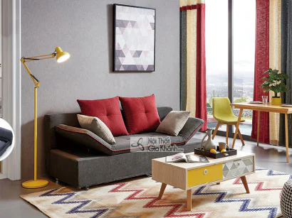 Sofa băng SF169-6 màu xám đậm đặt trong phòng khách hiện đại, chụp từ góc ngang. Sofa có tựa lưng và gối tựa màu đỏ, xám…