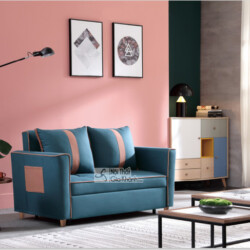 Sofa giường gấp SF1012B-3 màu xanh đậm với các đường viền và chi tiết túi trang trí màu hồng đất, đặt trong không gian phò…