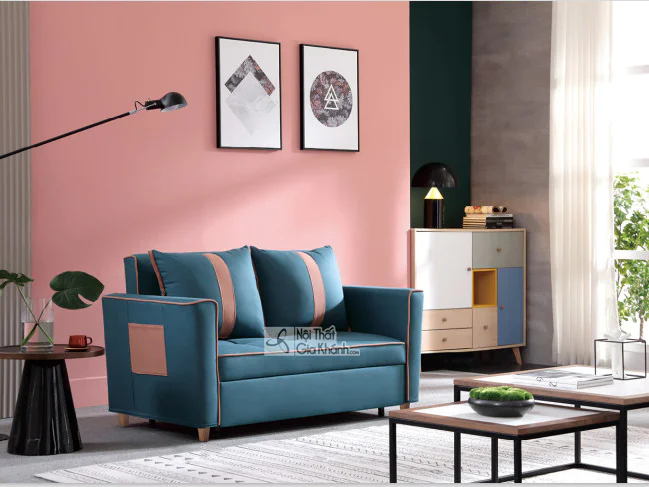 Sofa giường gấp SF1012B-3 màu xanh đậm với các đường viền và chi tiết túi trang trí màu hồng đất, đặt trong không gian phò…