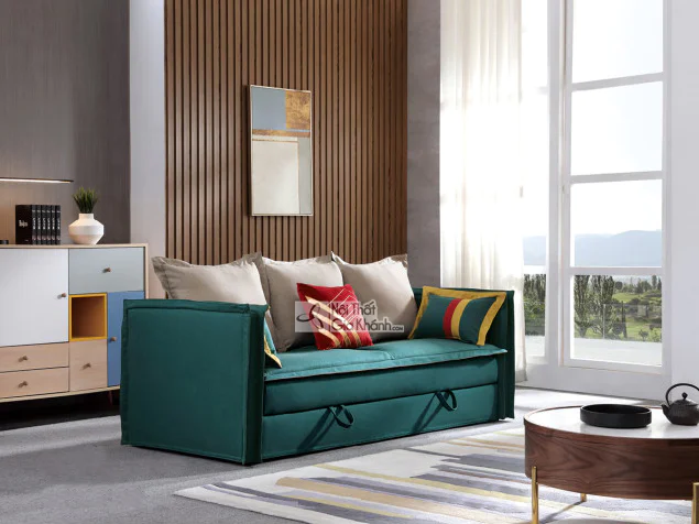 Sofa giường đa năng màu xanh ngọc bích, đặt trong phòng khách hiện đại với tường ốp gỗ và cửa sổ lớn. Sofa có thiết kế tối…