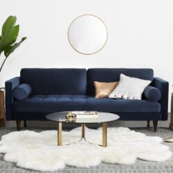 Sofa băng 3 chỗ bọc vải màu xanh cobalt đậm, đặt trong không gian phòng khách hiện đại với tường trắng, sàn gỗ và thảm lôn…