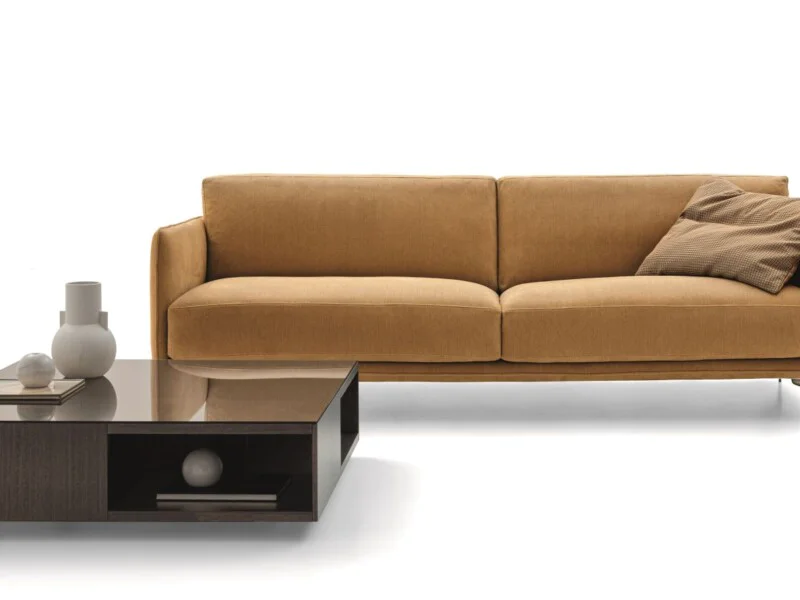 Sofa băng ba chỗ ngồi bọc vải màu nâu vàng ấm áp, chụp hơi chếch góc trên nền trắng studio. Thiết kế hiện đại với tay vịn…