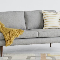 Sofa băng 3 chỗ Preston SF-111 màu xám nhạt, bọc vải, đặt trong phòng khách hiện đại. Sofa trang trí gối tựa trắng và chăn…