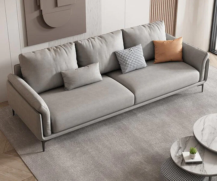 Sofa băng bọc da hiện đại Trudie SF-219 màu xám nhạt, chụp từ góc trên bên phải. Sofa có thiết kế thanh mảnh với chân kim…