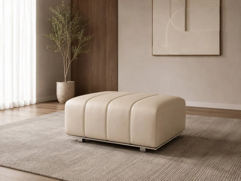 Ghế đôn sofa H361-100 màu kem nhạt, đặt trên thảm trải sàn màu be trong không gian phòng khách hiện đại. Ghế có kiểu dáng…