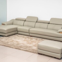 Bộ sofa góc chữ L SF672-Nano1-28 màu be/ghi sáng kết hợp với một đôn rời, đặt trên thảm lông màu kem trong một phòng khách…