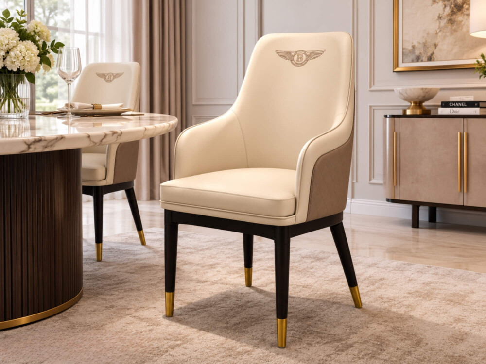 Ghế ăn Bentley bọc da màu kem nhạt, chân gỗ sồi đen bọc đồng vàng, đặt cạnh bàn ăn tròn mặt đá vân mây. Bối cảnh phòng ăn…