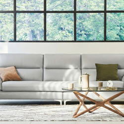 Sofa băng 3 chỗ CALMHAVEN màu xám nhạt, kiểu dáng hiện đại tối giản, đặt trong phòng khách có cửa sổ lớn. Sofa có đệm ngồi…