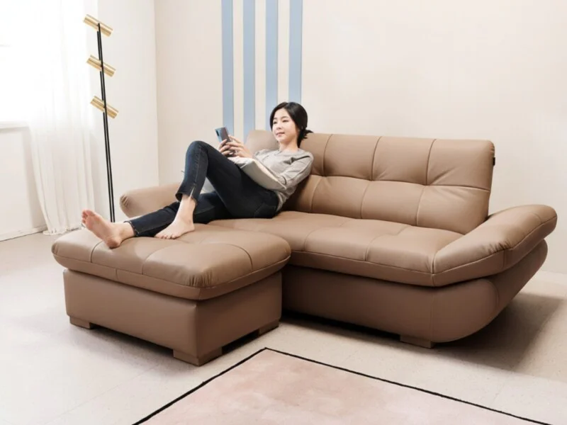 Hình ảnh tổng thể sofa SOFFLE màu nâu latte, kiểu dáng băng chữ L hiện đại, với một người phụ nữ đang ngồi thư giãn, tựa l…