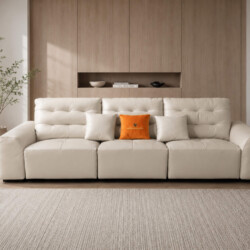 Sofa băng điện AUREO màu kem nhạt được chụp chính diện, đặt trong phòng khách phong cách tối giản. Tường ốp gỗ và thảm trả…