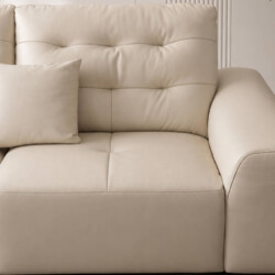 Cận cảnh phần tựa lưng và đệm ngồi của sofa AUREO màu kem nhạt, với các đường may rút lõm tinh tế tạo điểm nhấn. Chiếc gối…