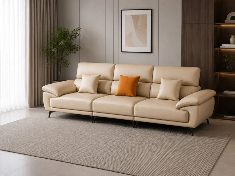 Sofa băng 3 chỗ SCULPT E008 màu kem nhạt, chụp góc hơi chéo từ phía trước, đặt trên thảm lông xám. Sofa có tựa lưng và tay…