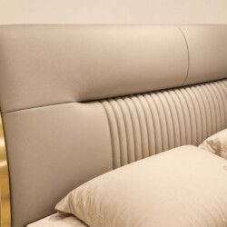 Cận cảnh phần đầu giường và một phần thân giường của GIQF918-18 từ góc nghiêng. Đầu giường bọc da màu be nhạt với các đườn…