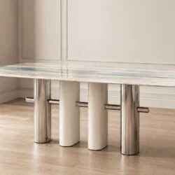 Bàn ăn CELESTIA mặt đá tinh thể 1m8, chụp góc thấp từ phía trước, nổi bật mặt đá trắng vân xám và ba chân trụ tròn lớn màu…