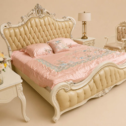 Giường MONARCHIA 1m8 trong bối cảnh phòng ngủ ấm cúng, chụp từ góc rộng. Giường có đầu và đuôi bọc da màu kem/vàng nhạt, k…