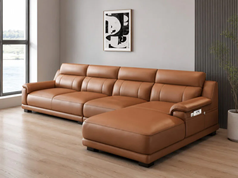Sofa VENTO góc L màu nâu caramel, chụp từ góc hơi chếch bên trái, cho thấy rõ chiều dài tổng thể và phần tựa lưng cao. Thi…