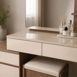 Cận cảnh mặt bàn phấn MILA từ góc nhìn trên cao, làm nổi bật bề mặt phẳng mịn và các ngăn kéo màu kem. Trên bàn bày trí gọ…