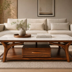 Bàn trà ARBOR đặt giữa không gian phòng khách ấm cúng, phía sau là bộ sofa màu kem nhạt, trên bàn có bình hoa và sách. Bàn…