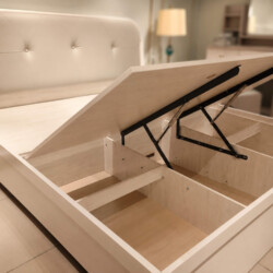 Giường ngủ ALTHEA GN2463 chụp góc chéo từ phía trước, với dát giường đang được nâng lên một phần, để lộ khoang chứa đồ bên…