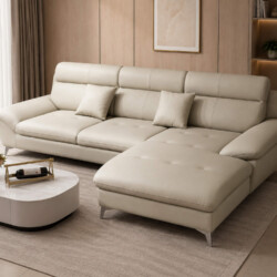 Sofa góc COASTAL II bọc da công nghiệp màu be nhạt, đặt trong phòng khách hiện đại với bàn trà mặt đá trắng và thảm. Góc c…