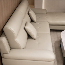 Sofa góc COASTAL II bọc da công nghiệp màu be nhạt, chụp từ góc nhìn phía sau bên phải. Tập trung vào phần tựa lưng và đệm…