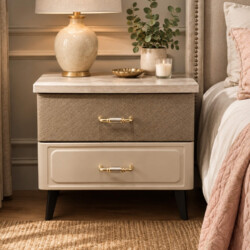 Tab đầu giường HAZEL góc chụp hơi nghiêng, đặt cạnh giường ngủ với chăn màu hồng. Tủ có mặt trên vân gỗ, hai ngăn kéo màu…
